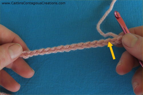 completed chain stitches with yellow arrow showing where to insert hook for next stitch.