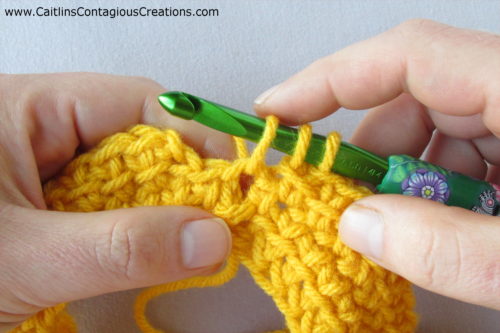 mustard yarn with 3 loops on green hook