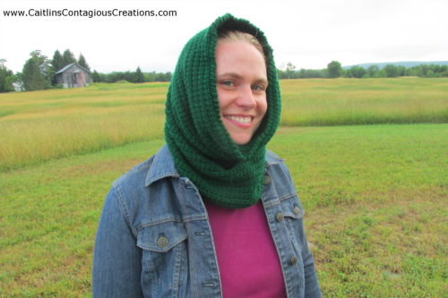 Linked for Life Hooded Cowl Crochet Pattern finished project worn by model in grassy field.