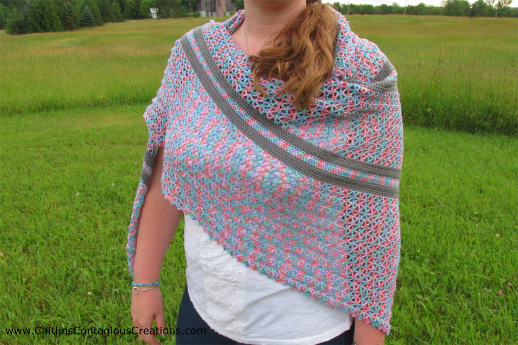 model wearing summer nights triangle shawl crochet pattern in grassy hillside