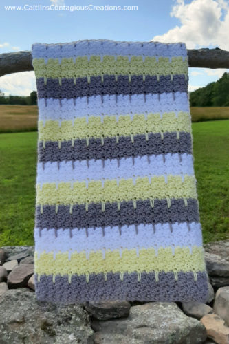 finished lemon squeezy baby blanket crochet project hanging in a sunny field