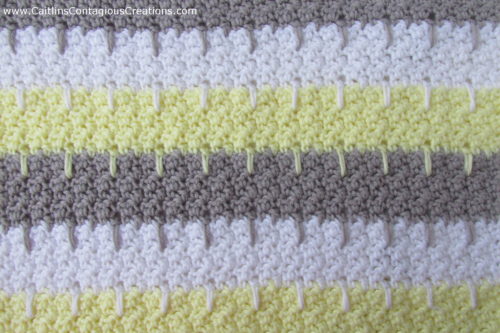 close up of texture of blanket. grey yellow and white alternating stripes