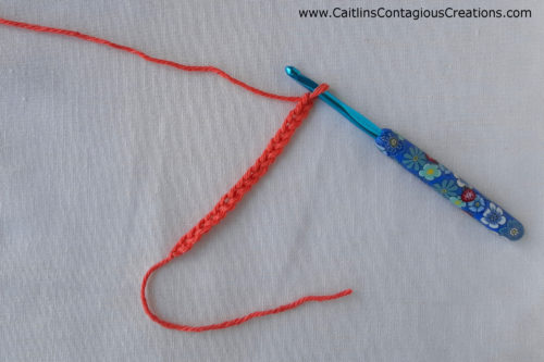 chain of 10 crochet sttiches made from red yarn and a blue crochet hook