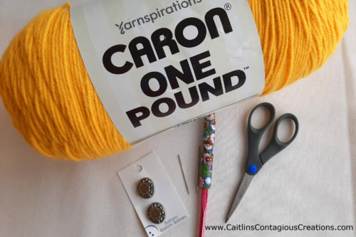 materials needed for cowl free crochet pattern include worsted weight yarn, yellow is pictured, an I9 crochet hook, scissors, a needle, and 4 buttons.
